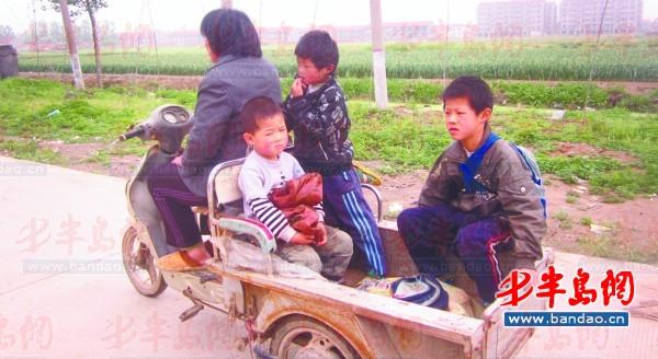 2011年底一名孩子在三輪車上趕作業(yè)。一年半過去了，這樣的場景仍隨處可見。
