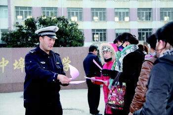 交警在學(xué)校門口向家長(zhǎng)發(fā)放校車安全宣傳單(資料片)。